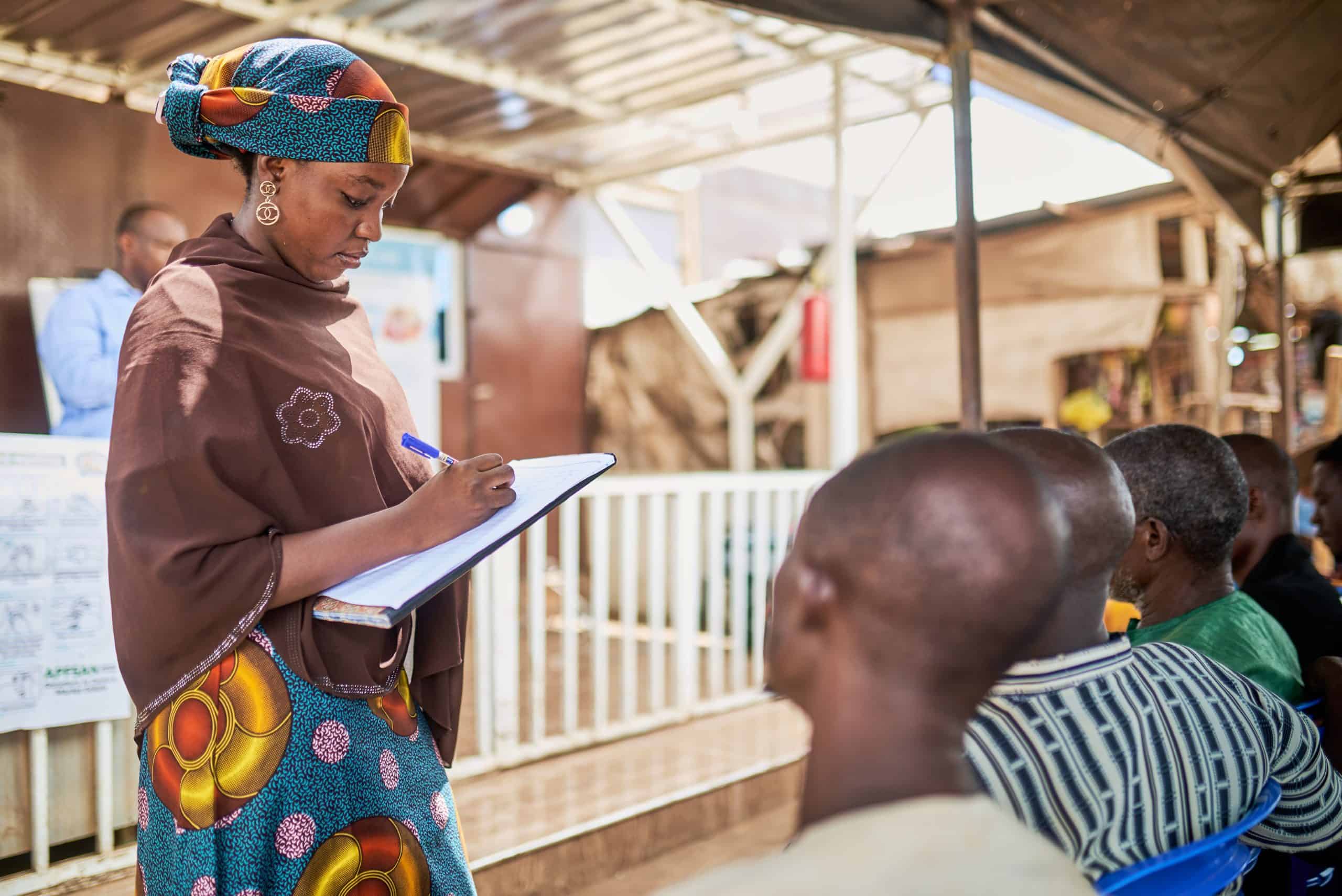 Woman taking notes during a health education session with workers.