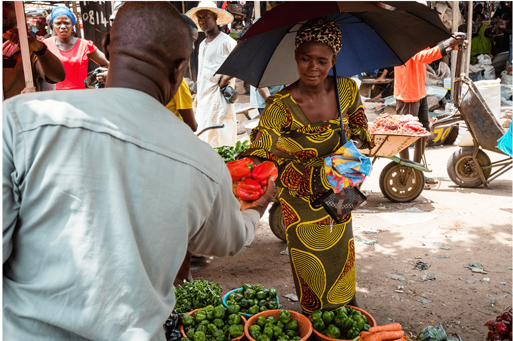 Woman selling fresh vegetables at market promoting nutrition and climate resilience.
